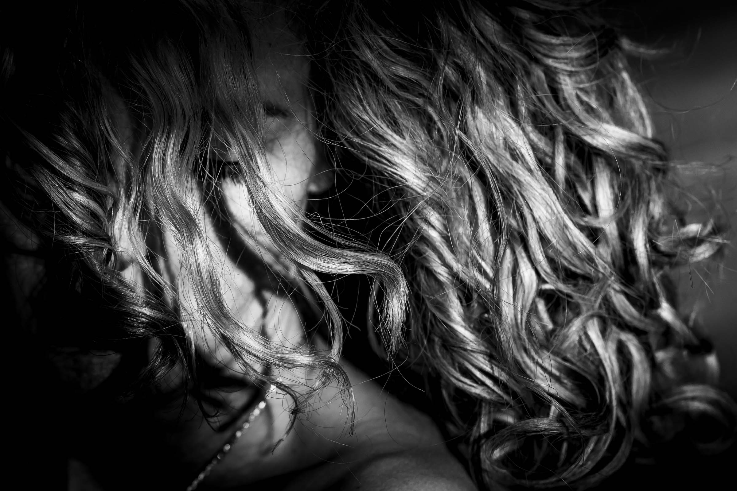 Zwart-witportret van een vrouw met krullen in het licht, Sandra Koppelaar Fotografie