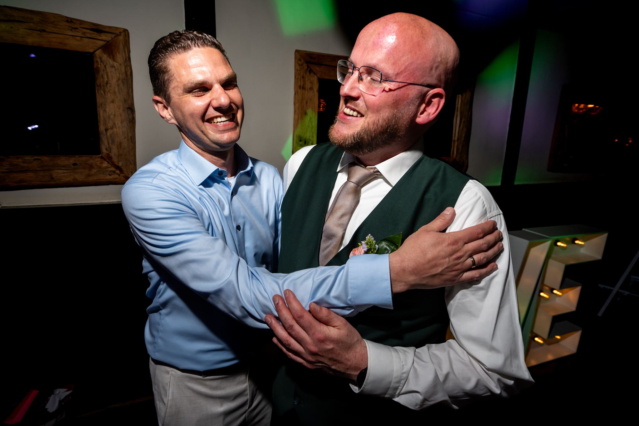 Bruidegom en een gast lachen samen op het bruiloftsfeest in Delft, documentaire trouwfotografie