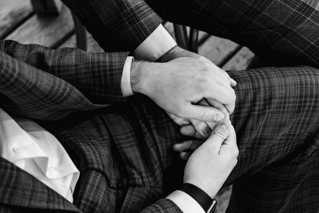 Handen van de bruidegoms tijdens de ceremonie, zwart-wit documentaire trouwfotografie