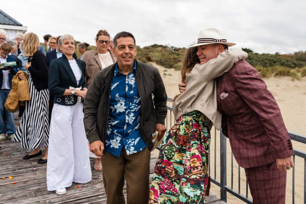 Gasten feliciteren de bruidegoms op het terras van Our Seaside in Renesse
