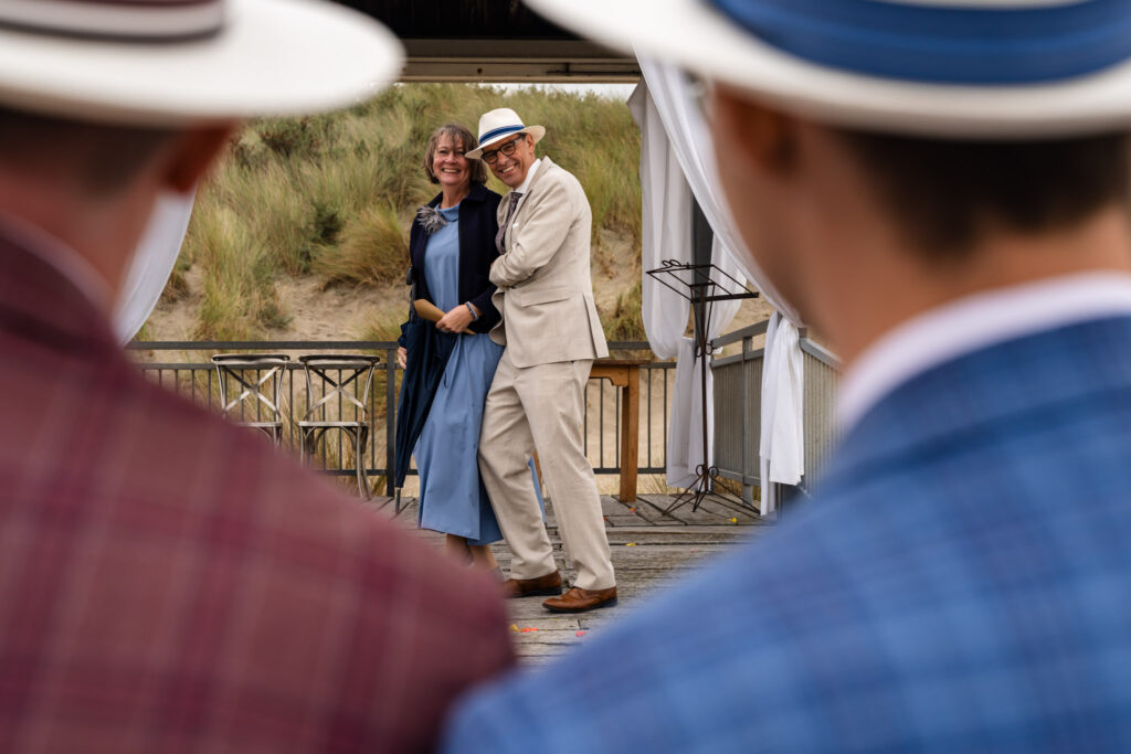 Familie bij het strandpaviljoen, gezien tussen de bruidegoms door, in Renesse