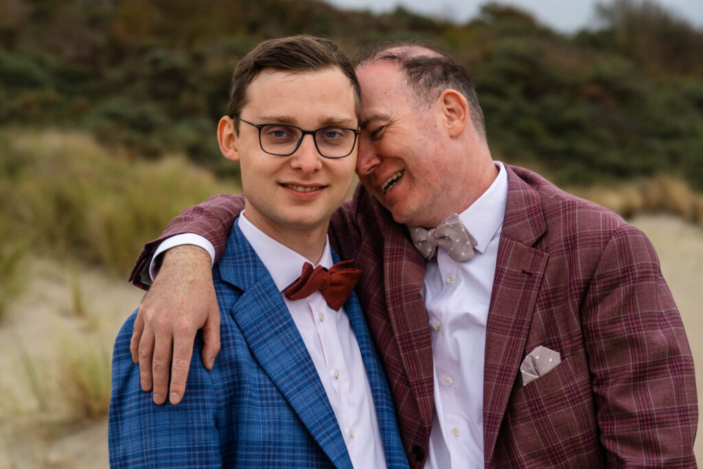 Bruidegoms lachen samen in de duinen van de Zeeuwse kust