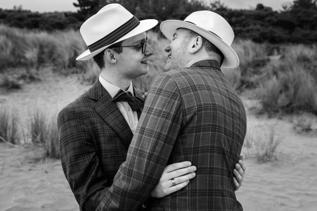 Bruidegoms met hoeden in de duinen van Renesse, zwart-wit couplefotoshoot