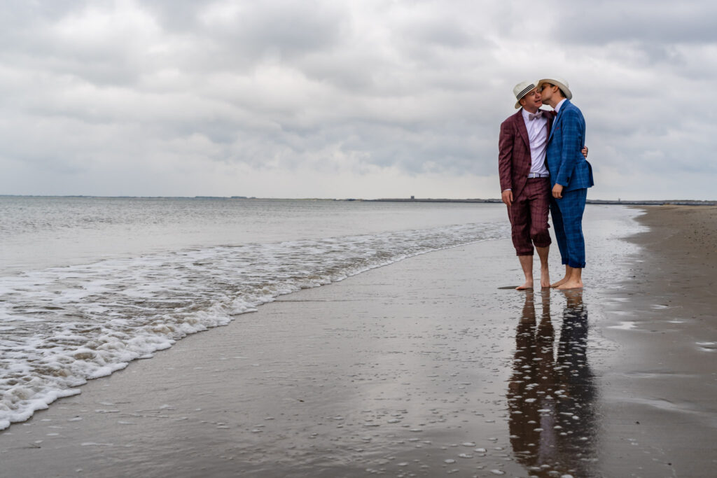Bruidegoms kussen aan de vloedlijn op het strand van Renesse