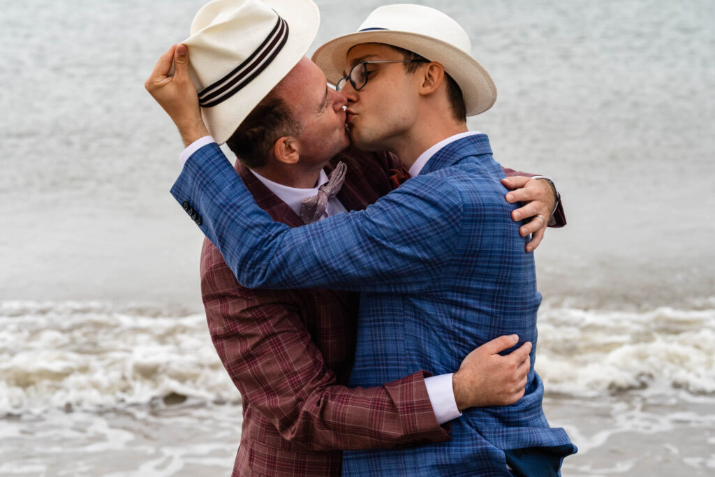 Bruidegoms kussen bij de zee in Renesse tijdens de couplefotoshoot