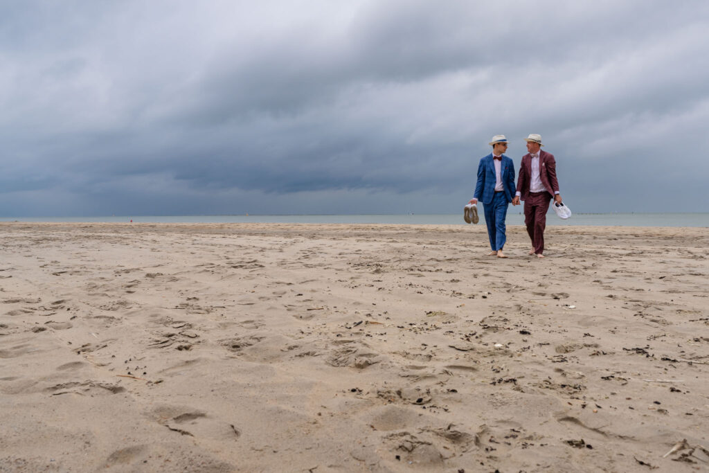 Bruidegoms lopen samen over het lege strand van Renesse