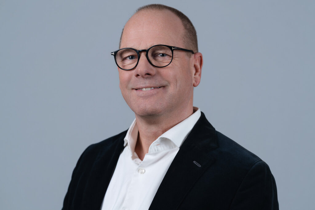 Zakelijk portret van een man met bril en colbert voor een grijze achtergrond