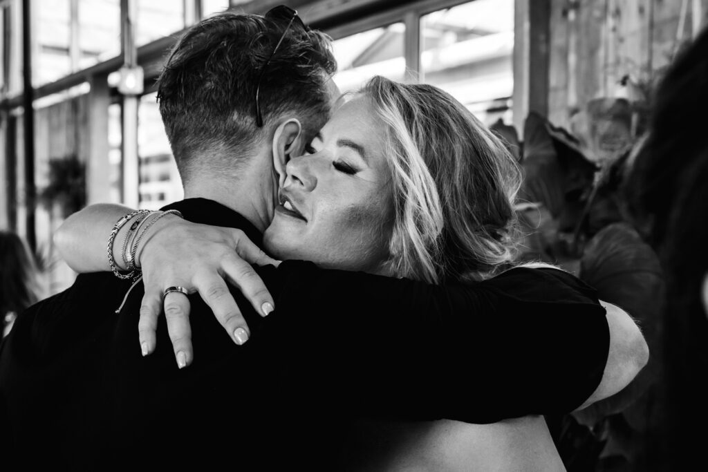 Bruid omhelst een gast na de ceremonie, documentaire trouwfotografie in zwart-wit